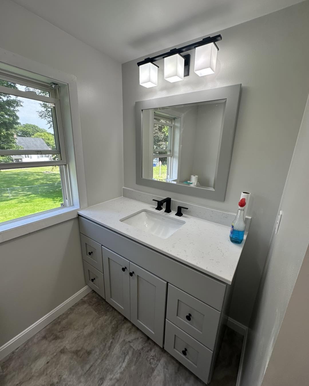 Bathroom after remodel — new gray vanity, modern fixtures, fresh tile