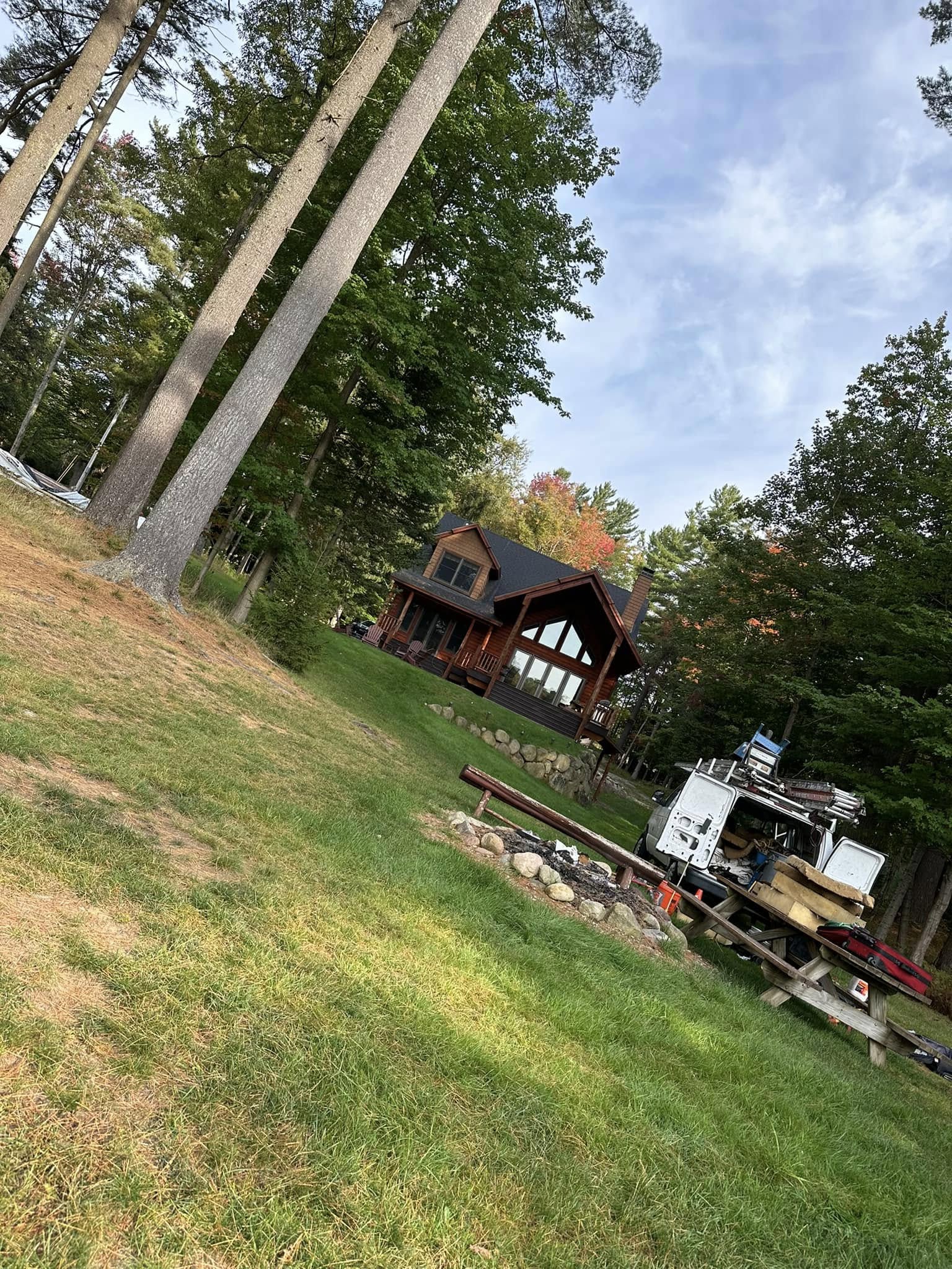 Finished exterior — cedar siding, black roof, and covered porch nestled in the trees