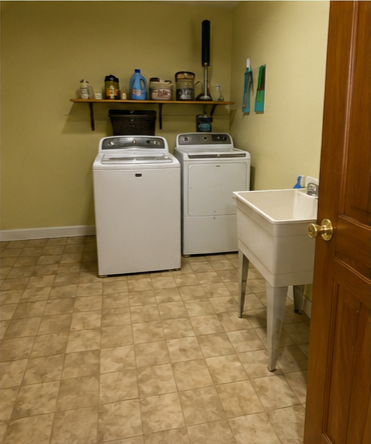 Laundry room before renovation &mdash; dated tile floor, yellow walls, and utility sink